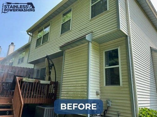 Before power washing exterior of a two-story home with a wooden deck and window views.