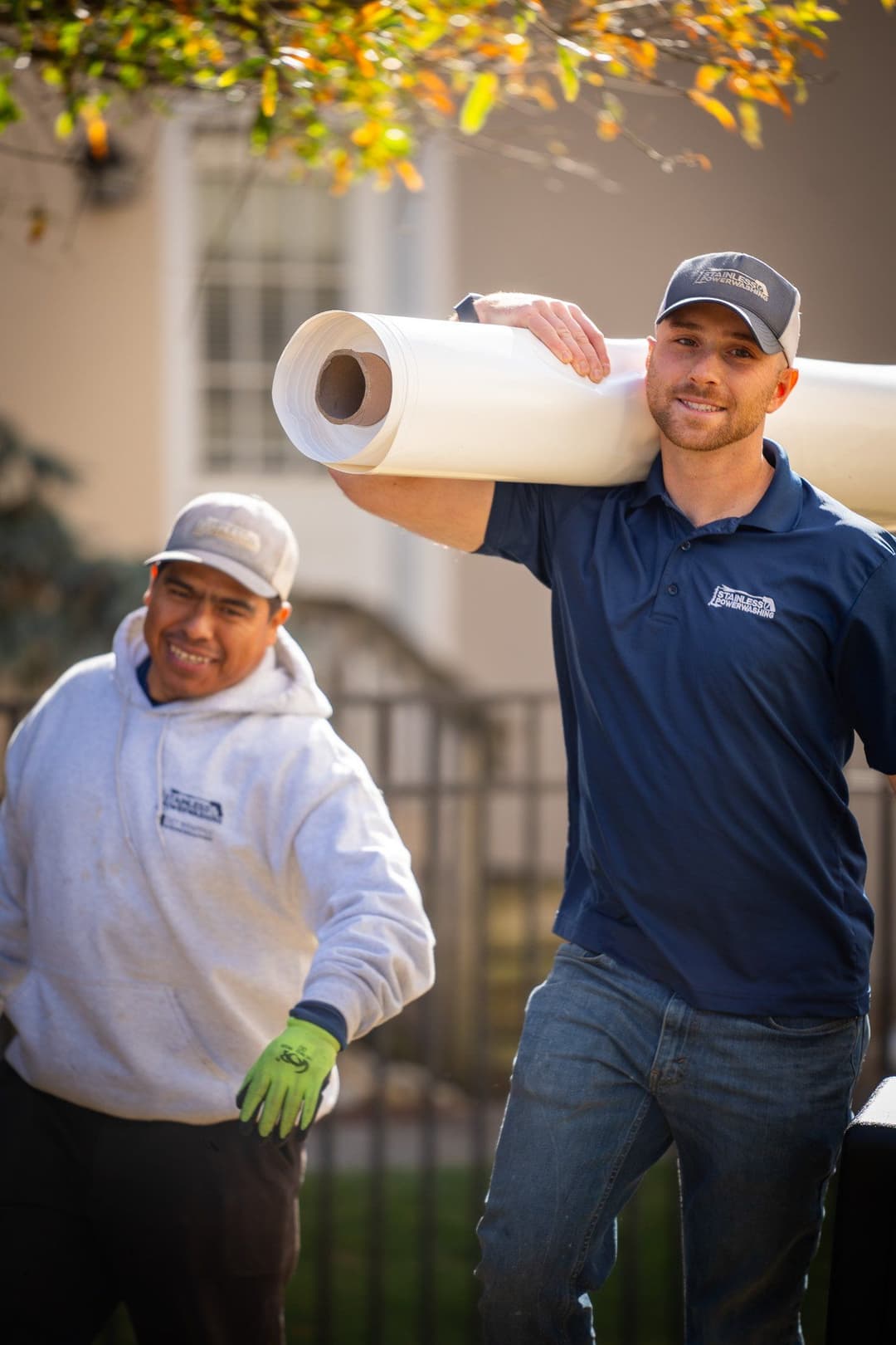 Two construction workers carrying large rolls of material, ready for a project.