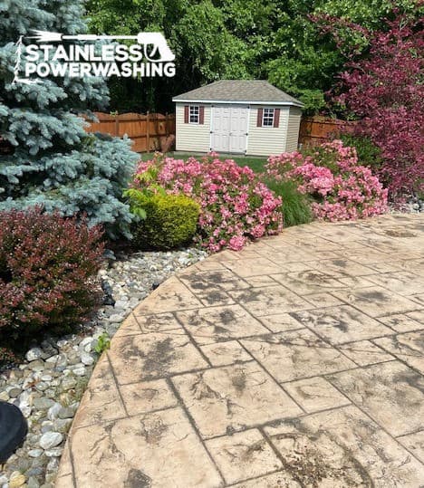 Well-maintained backyard featuring a landscaped patio, colorful flowers, and a garden shed.