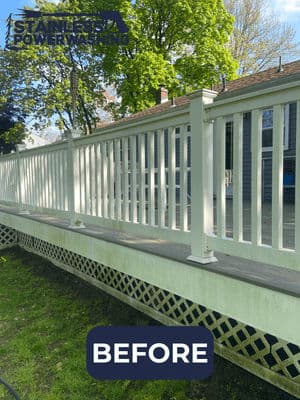 Before power washing, unsightly dirty deck railing and fence in a residential yard.