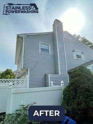 After power washing home exterior, showcasing clean siding and chimney with sunlight.