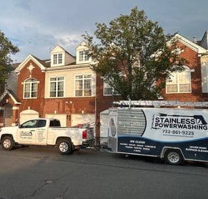 Stainless Powerwashing truck and trailer parked in front of a residential building.